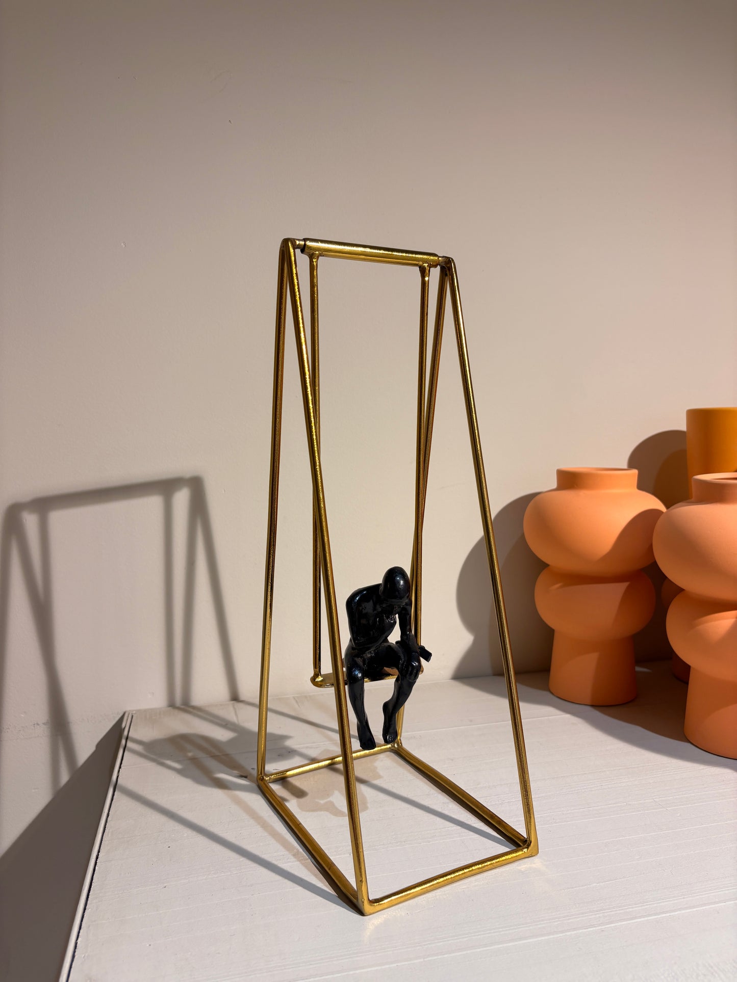 "Thinker Man" figure seated on a swing