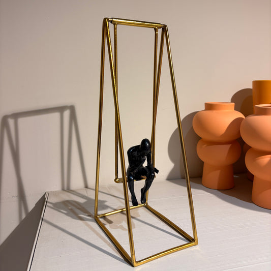 "Thinker Man" figure seated on a swing